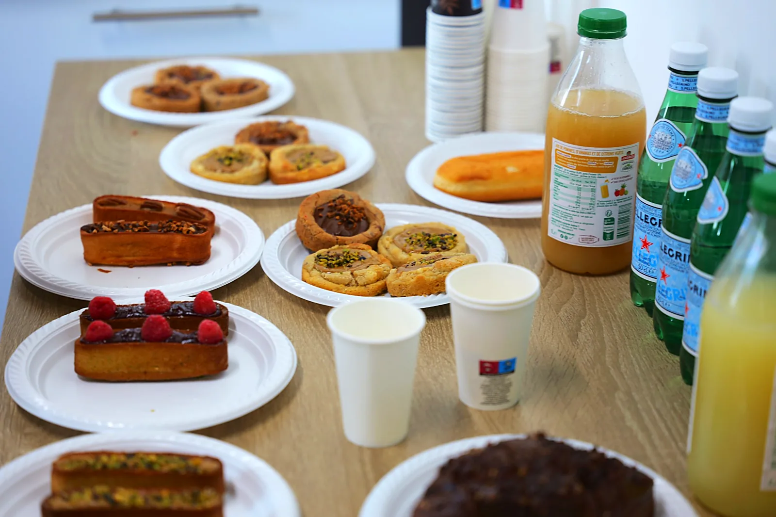 Table de pâtisseries, jus de fruits, eaux pétillantes et gobelets à café