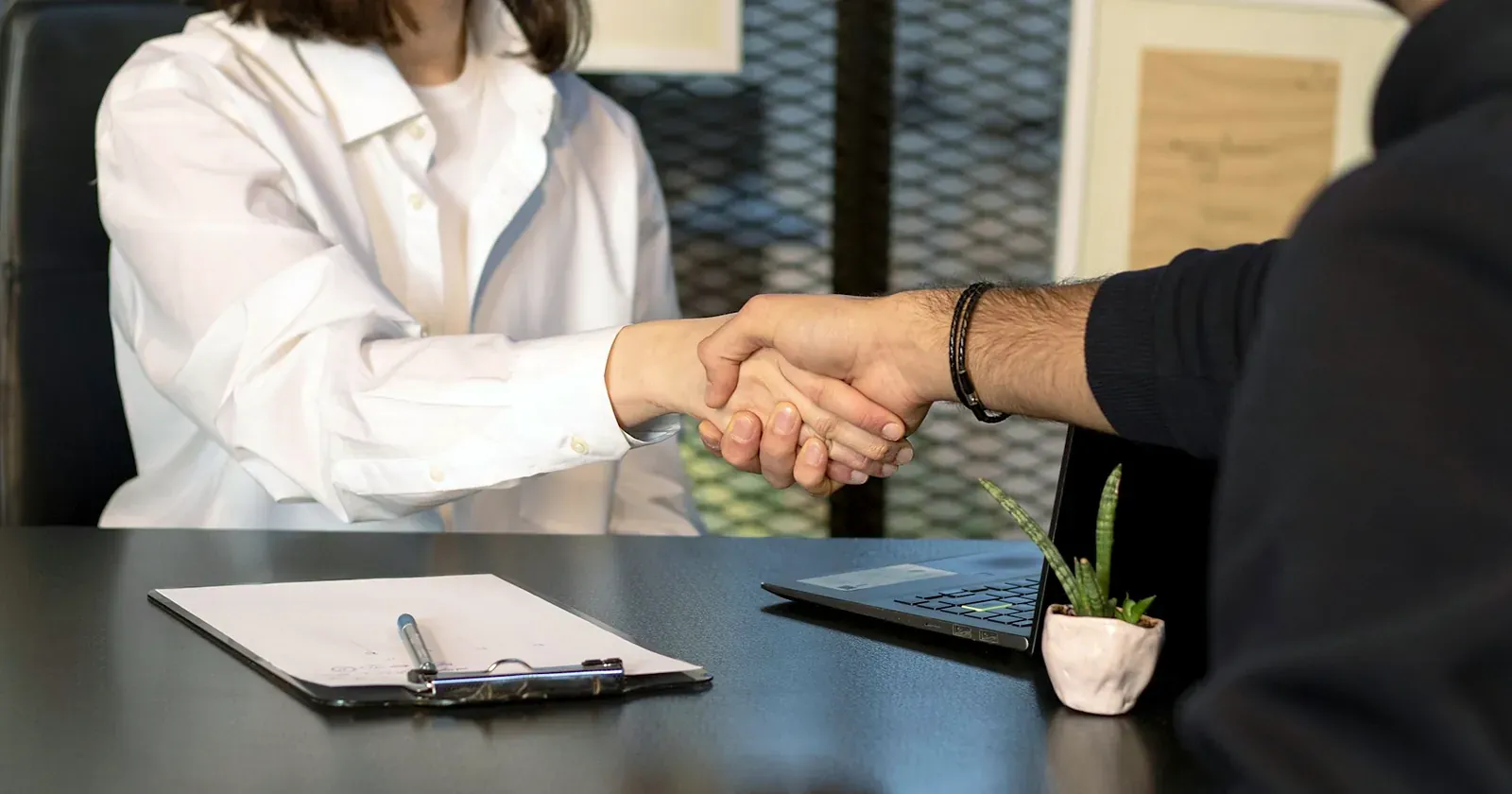 Poignée de main au-dessus d'un bureau lors d'un entretien de recrutement