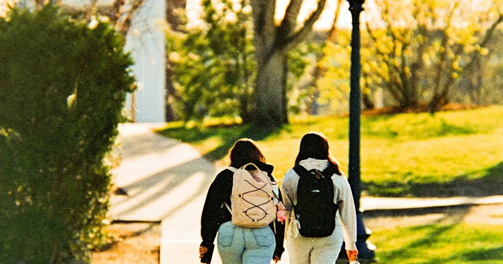 Deux étudiants avec leur sac à dos marchent dans un parc